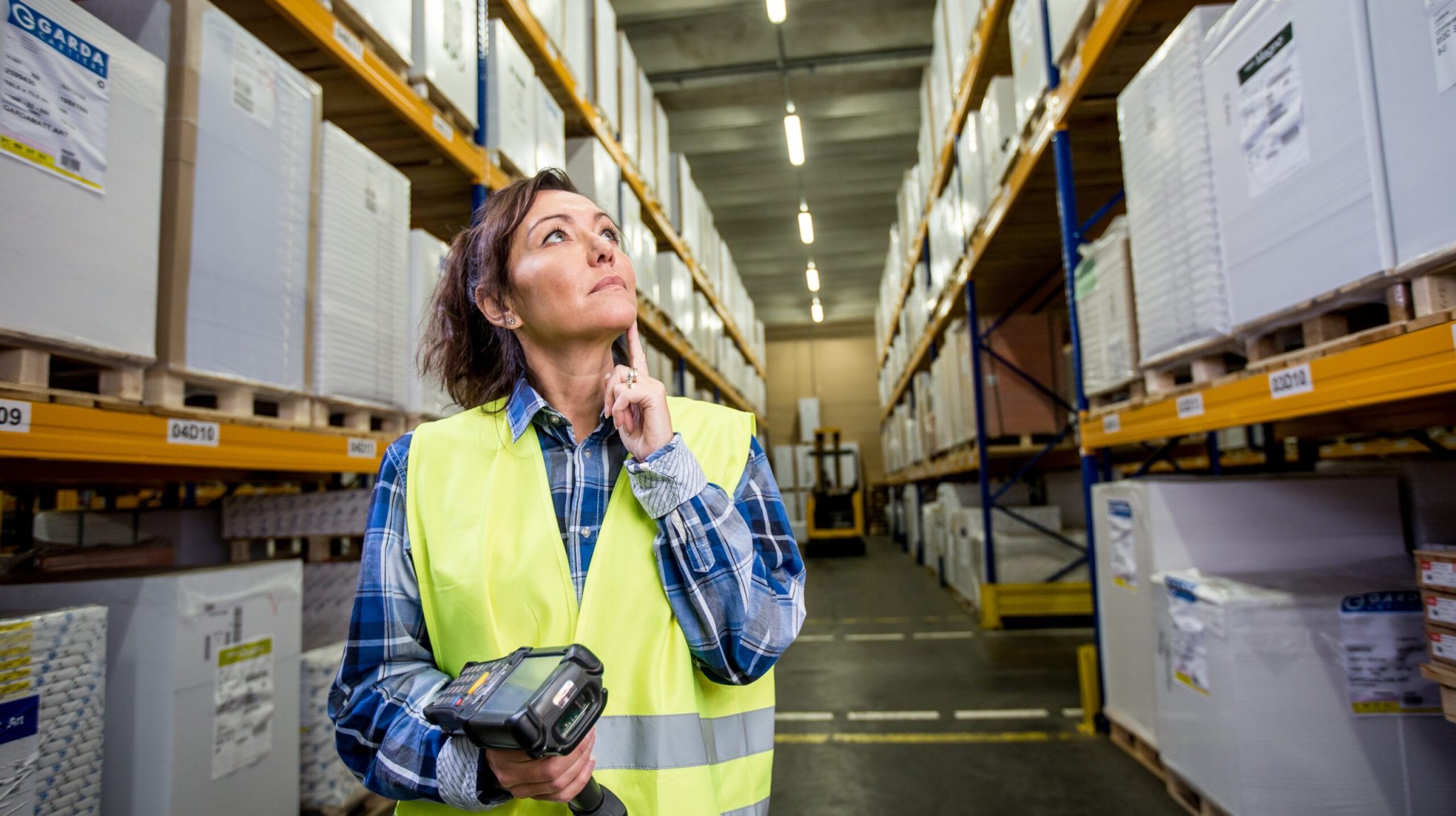 Puzzled,Woman,In,Warehouse,Working,With,Hand,Scanner,And,Looking